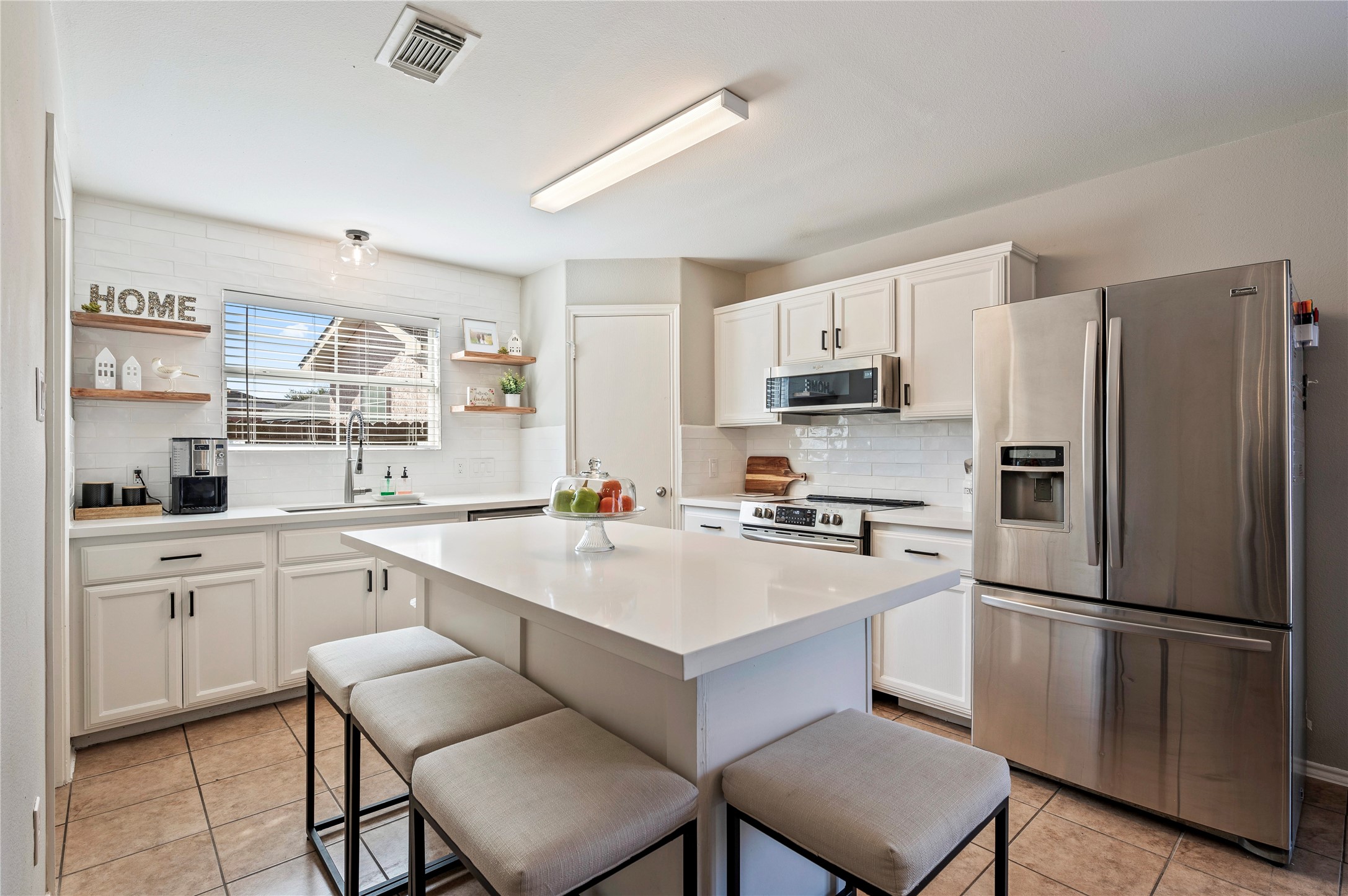 a kitchen with a refrigerator a stove a sink and white cabinets