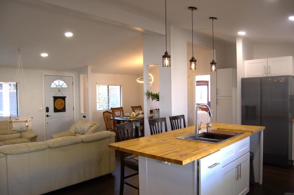 a living room with stainless steel appliances kitchen island a table chairs sink and mirror
