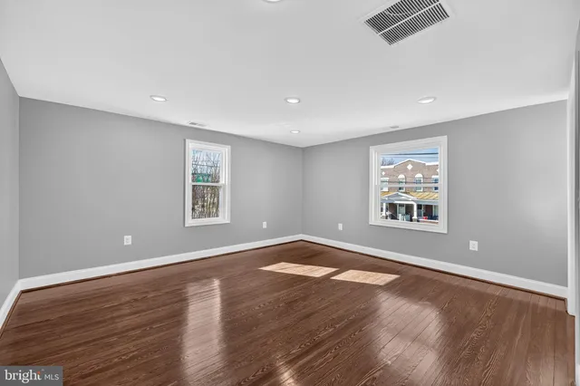a view of an empty room with wooden floor and closet