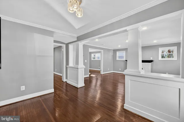 a view of empty room with wooden floor and kitchen view