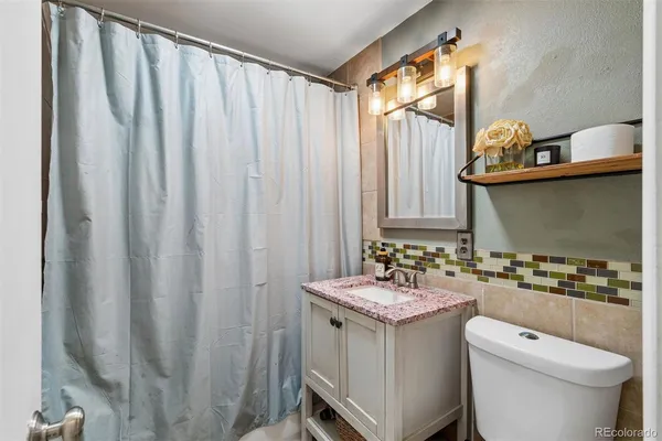 a bathroom with a granite countertop sink and a toilet