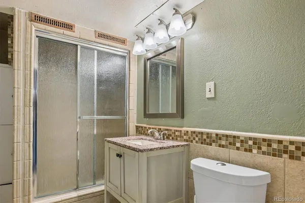 a bathroom with a granite countertop sink a toilet and shower