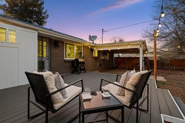 a view of a patio with a dining table and chairs with wooden floor and fence