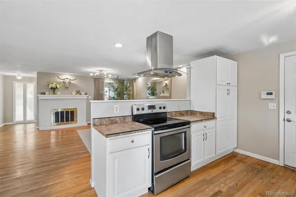 a kitchen with a stove and wooden floor