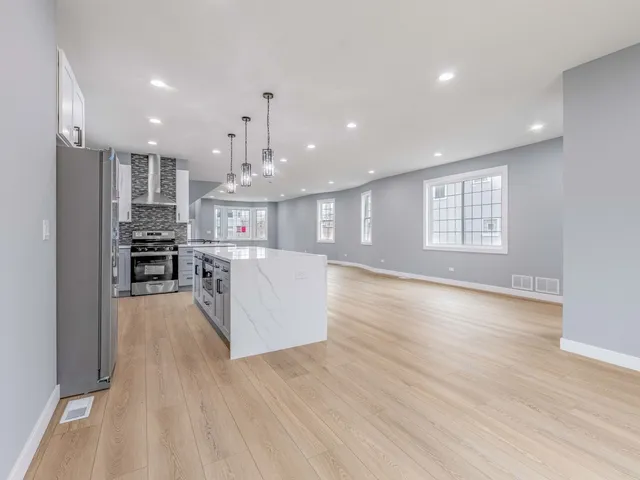 a view of kitchen with kitchen island wooden floor center island and stainless steel appliances