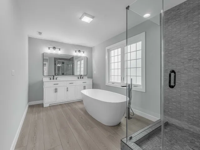 a spacious bathroom with a double vanity sink a mirror and a bathtub