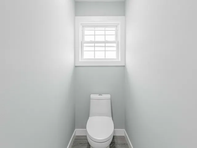 a white toilet sitting in a bathroom next to a window