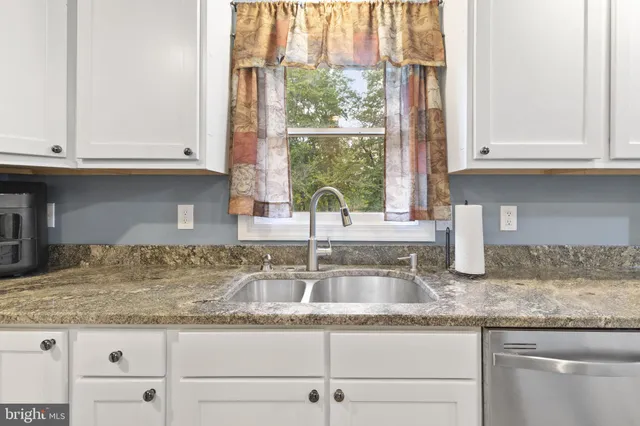 a kitchen with granite countertop a refrigerator sink and cabinets