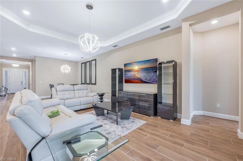 8448 Rosa Court Naples, FL 34114 - Photo 7 of 24 Living area featuring wood-finish flooring, recessed lighting, crown molding, and a tray ceiling