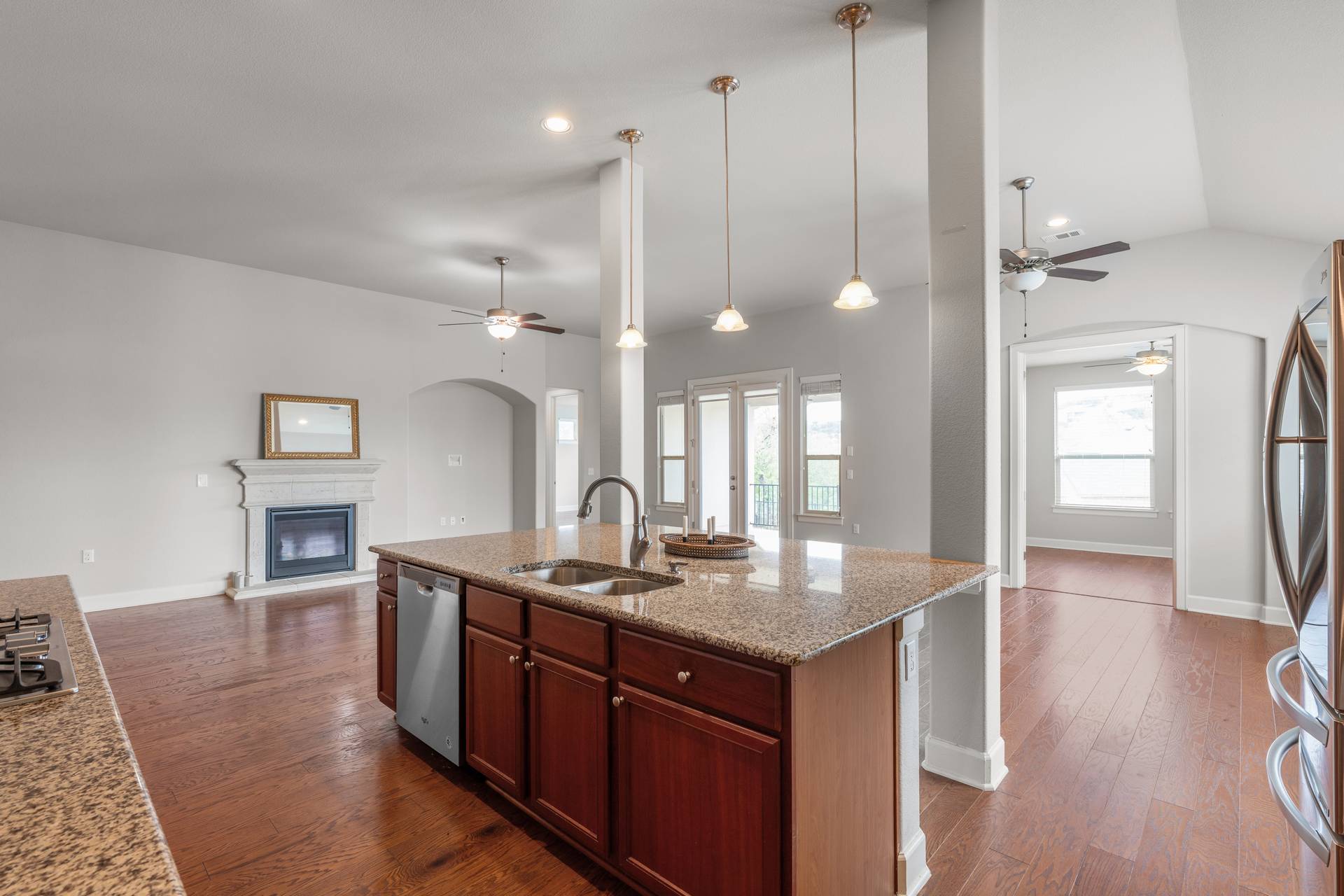 3516 Venezia View Leander, TX 78641 - Photo 40 of 40 Kitchen with a ceiling fan, dark wood-style flooring, open floor plan, a glass covered fireplace, and vaulted ceiling