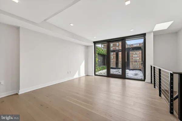 a view of an empty room with wooden floor and fan