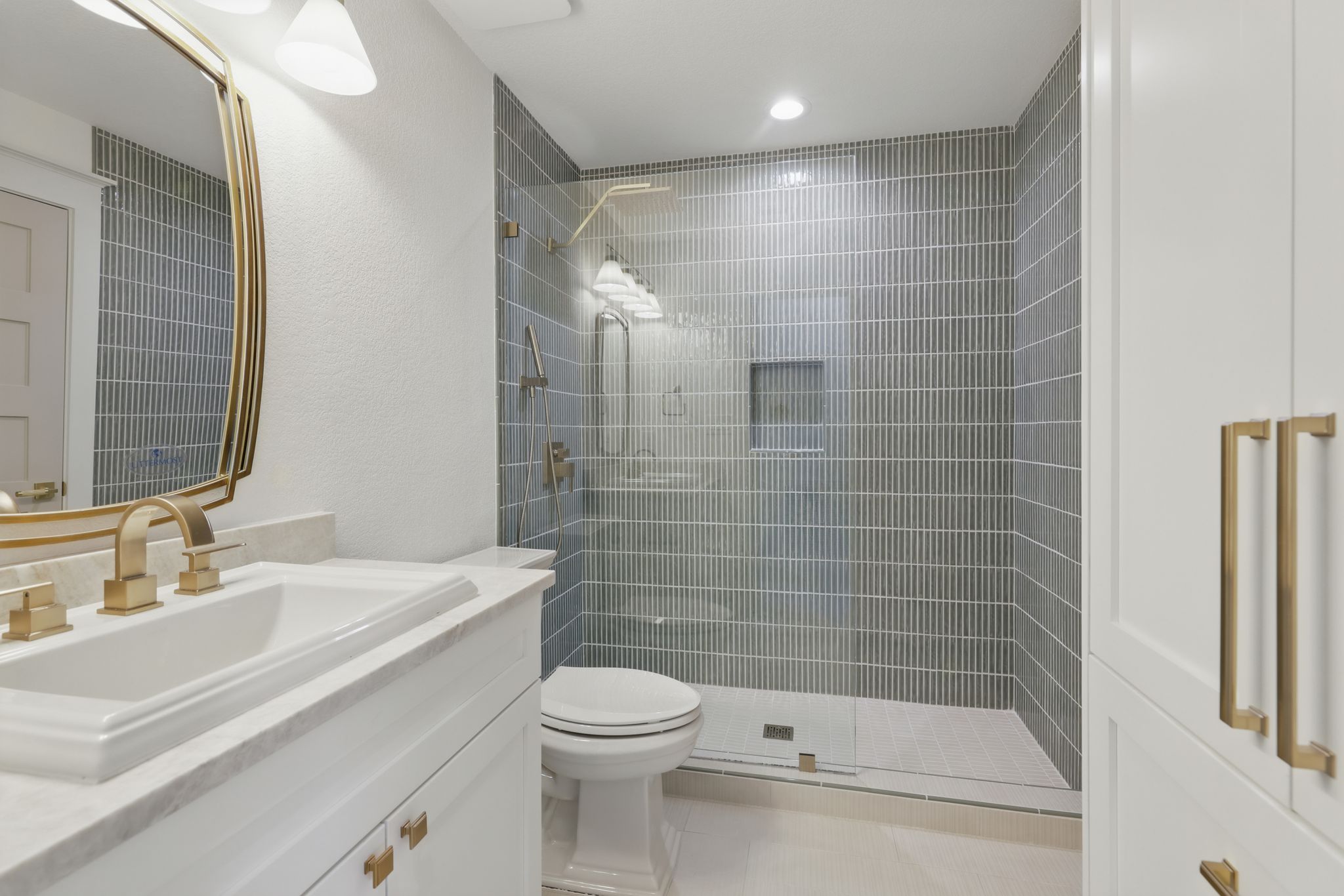 6905 Rudi Cove Austin, TX 78759 - Photo 16 of 37 A refined bathroom featuring a glass-enclosed shower with subway tile, a vanity, and elegant gold hardware.