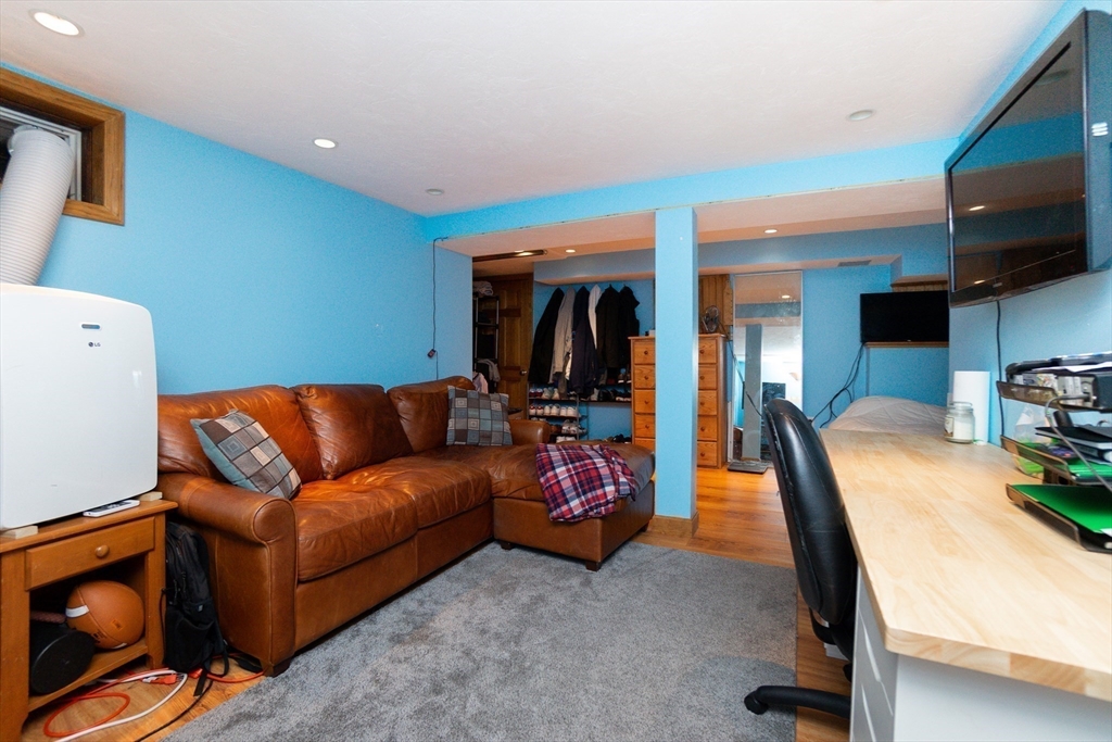 35 Hamilton Road Waltham, MA 02453 - Photo 26 of 38 a living room with furniture a flat screen tv and gym equipment
