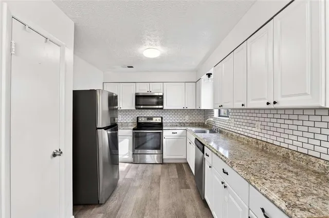 a kitchen with stainless steel appliances granite countertop a sink a stove a microwave and cabinets