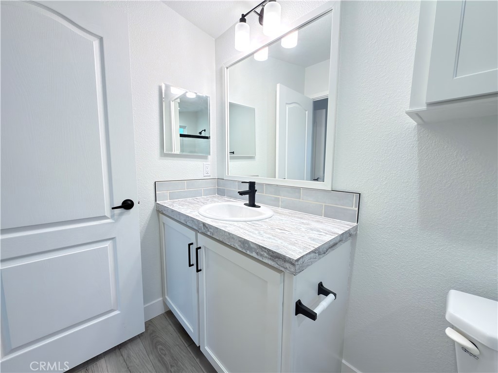 13061 Fairview Street, Unit 22 Garden Grove, CA 92843 - Photo 19 of 25 a bathroom with a granite countertop sink a toilet and a mirror