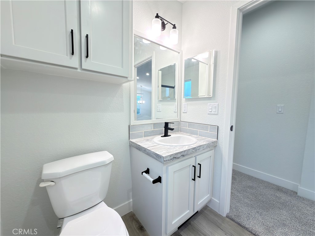 13061 Fairview Street, Unit 22 Garden Grove, CA 92843 - Photo 20 of 25 a bathroom with a granite countertop toilet sink and mirror
