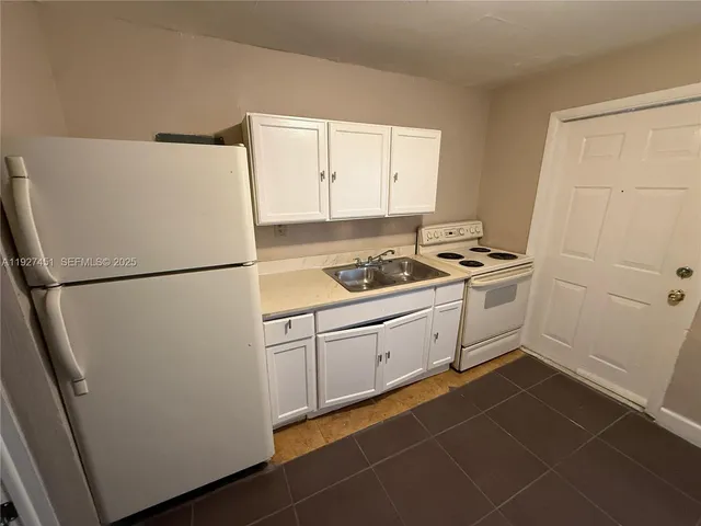 a white refrigerator freezer and a stove sitting inside of a kitchen