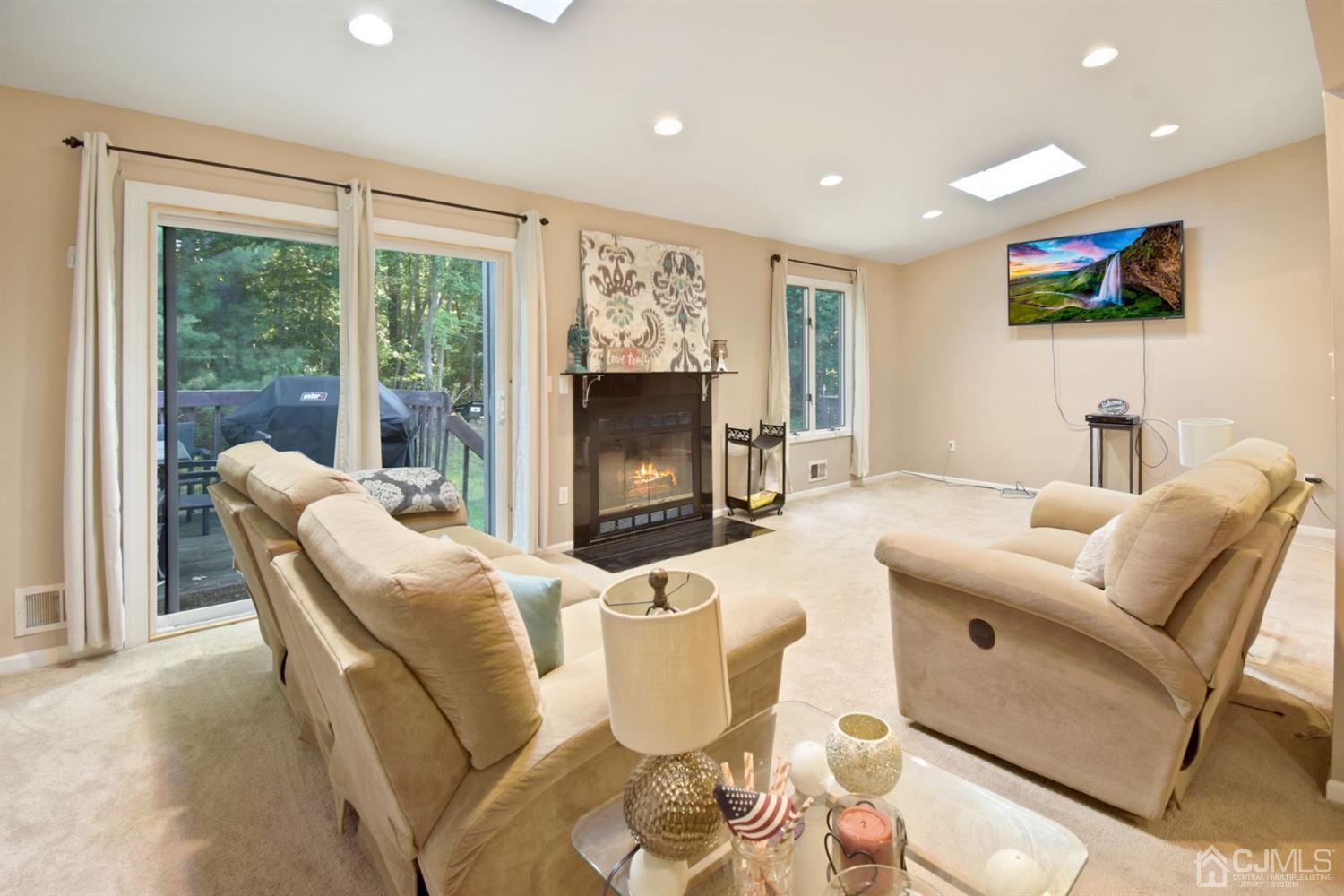 119 Redpine Loop Old Bridge, NJ 08857 - Photo 2 of 15 a living room with furniture a flat screen tv and a floor to ceiling window