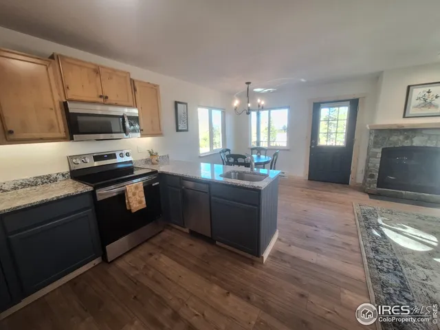 a kitchen with granite countertop a stove top oven a sink dishwasher and a refrigerator with wooden floor