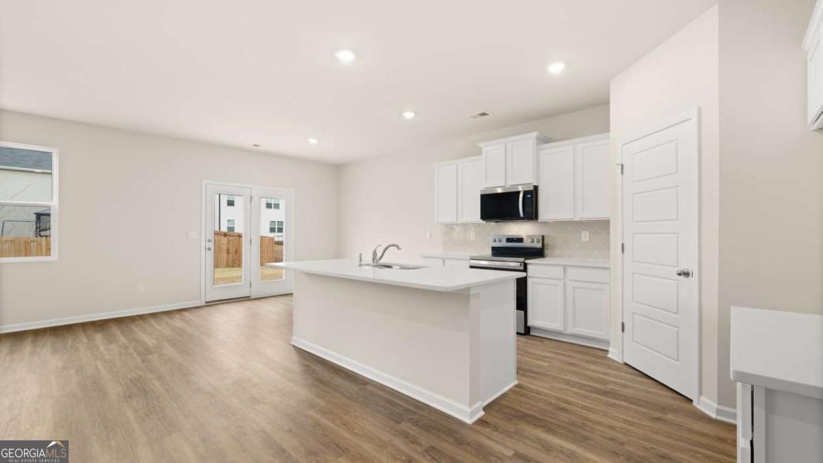 202 Cattle Drive Perry, GA 31069 - Photo 7 of 30 a kitchen with stainless steel appliances a stove a sink a refrigerator white cabinets and wooden floor