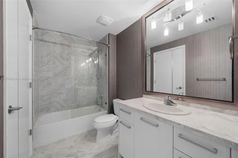 a bathroom with a granite countertop sink a toilet and shower