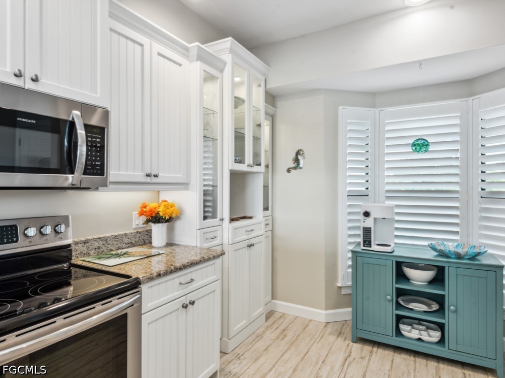 232 La Peninsula Boulevard, Unit 232 Naples, FL 34113 - Photo 7 of 44 a kitchen with granite countertop stainless steel appliances a stove cabinets and wooden floor