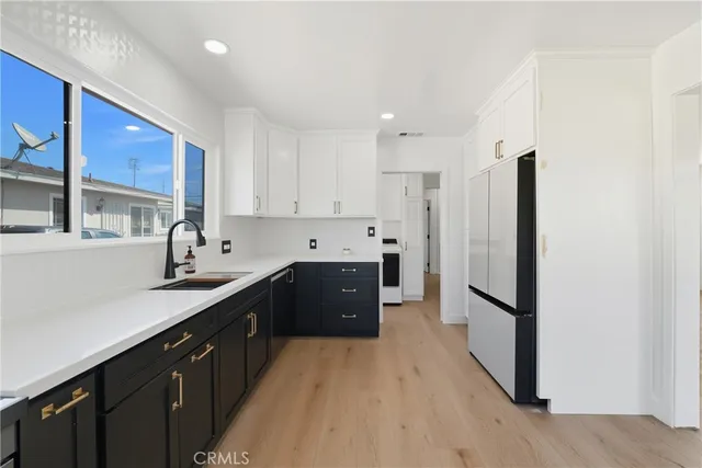 a kitchen with stainless steel appliances granite countertop a refrigerator a sink dishwasher and a stove with wooden floor