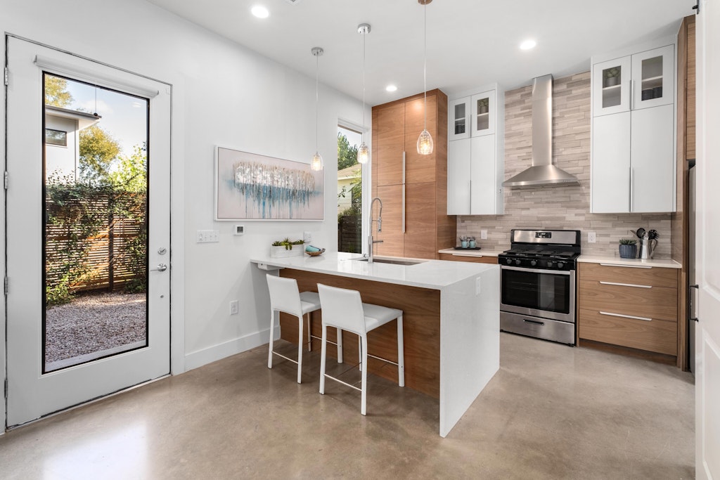 2909 East 13th Street, Unit 2 Austin, TX 78702 - Photo 7 of 23 Kitchen with a peninsula, a kitchen bar, two tone cabinets, finished concrete flooring, and glass fronted cabinets