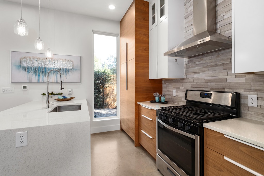 2909 East 13th Street, Unit 2 Austin, TX 78702 - Photo 8 of 23 Kitchen with stainless steel gas range, dual tone cabinetry, light stone counters, pendant lighting, and glass insert cabinets