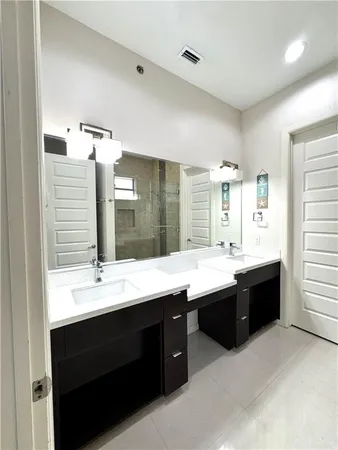 a large bathroom with a double vanity sink a large mirror and bathtub
