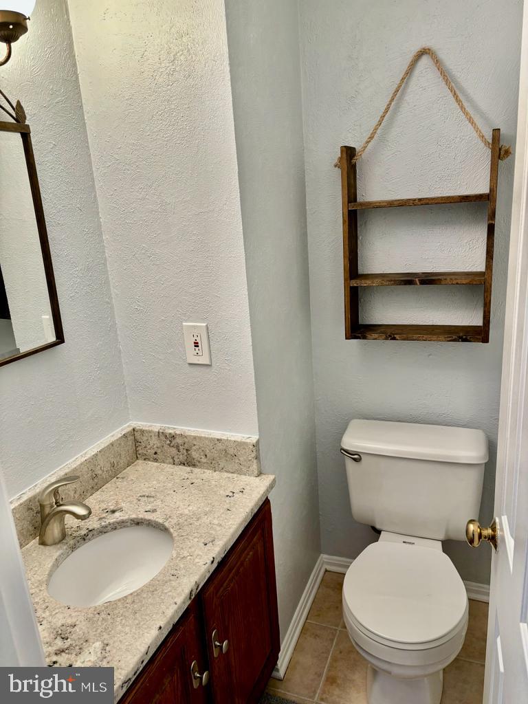 6803 Wild Rose Court Springfield, VA 22152 - Photo 38 of 49 a bathroom with a granite countertop toilet sink and mirror