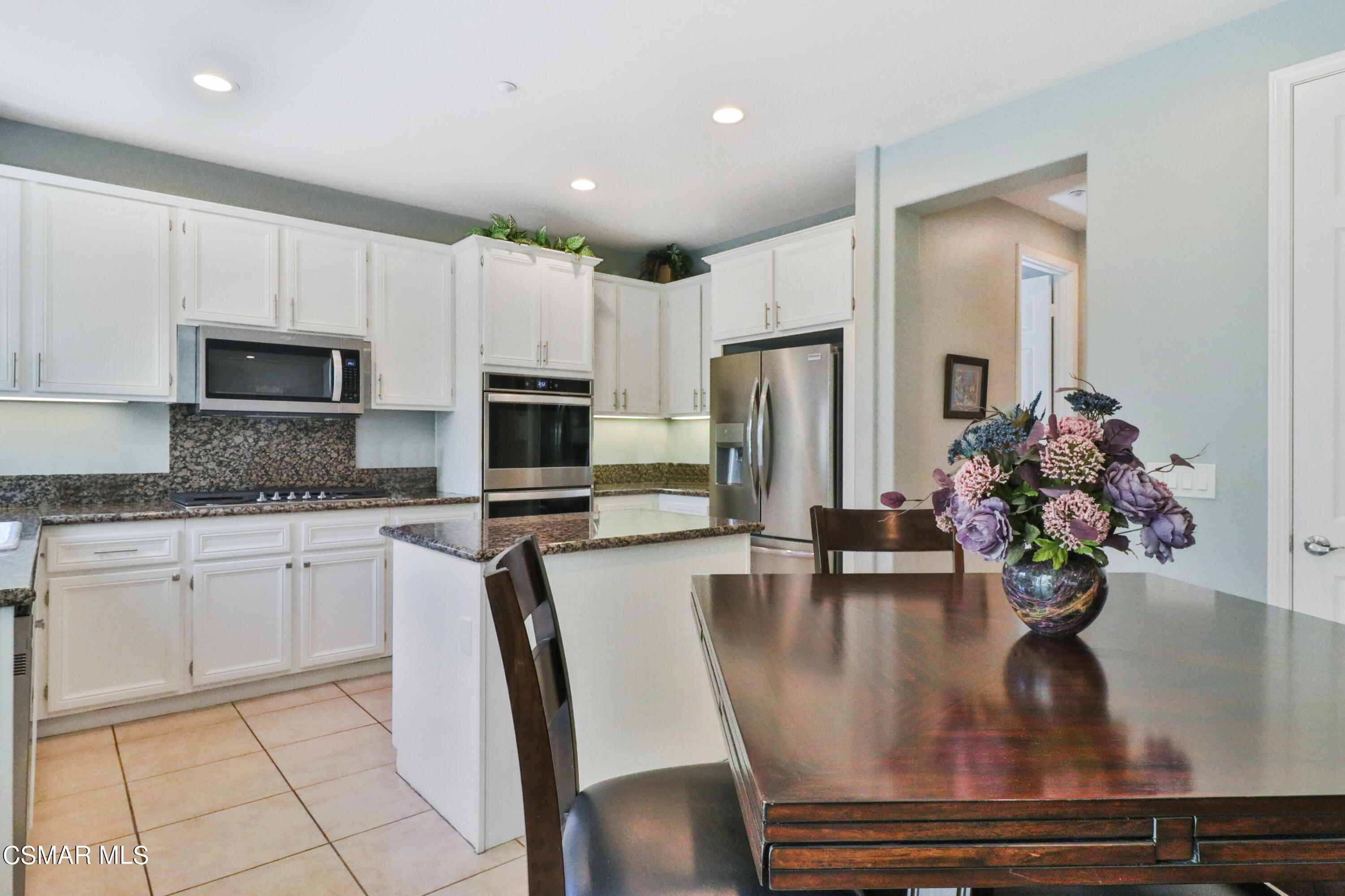 1419 Hidden Ranch Drive Simi Valley, CA 93063 - Photo 13 of 50 a kitchen with stainless steel appliances granite countertop a refrigerator a stove a microwave oven with a dining table and chairs
