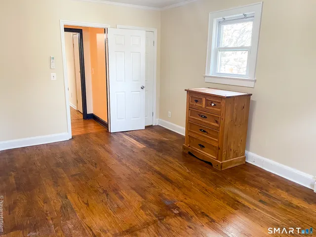 an empty room with wooden floor cabinet and windows