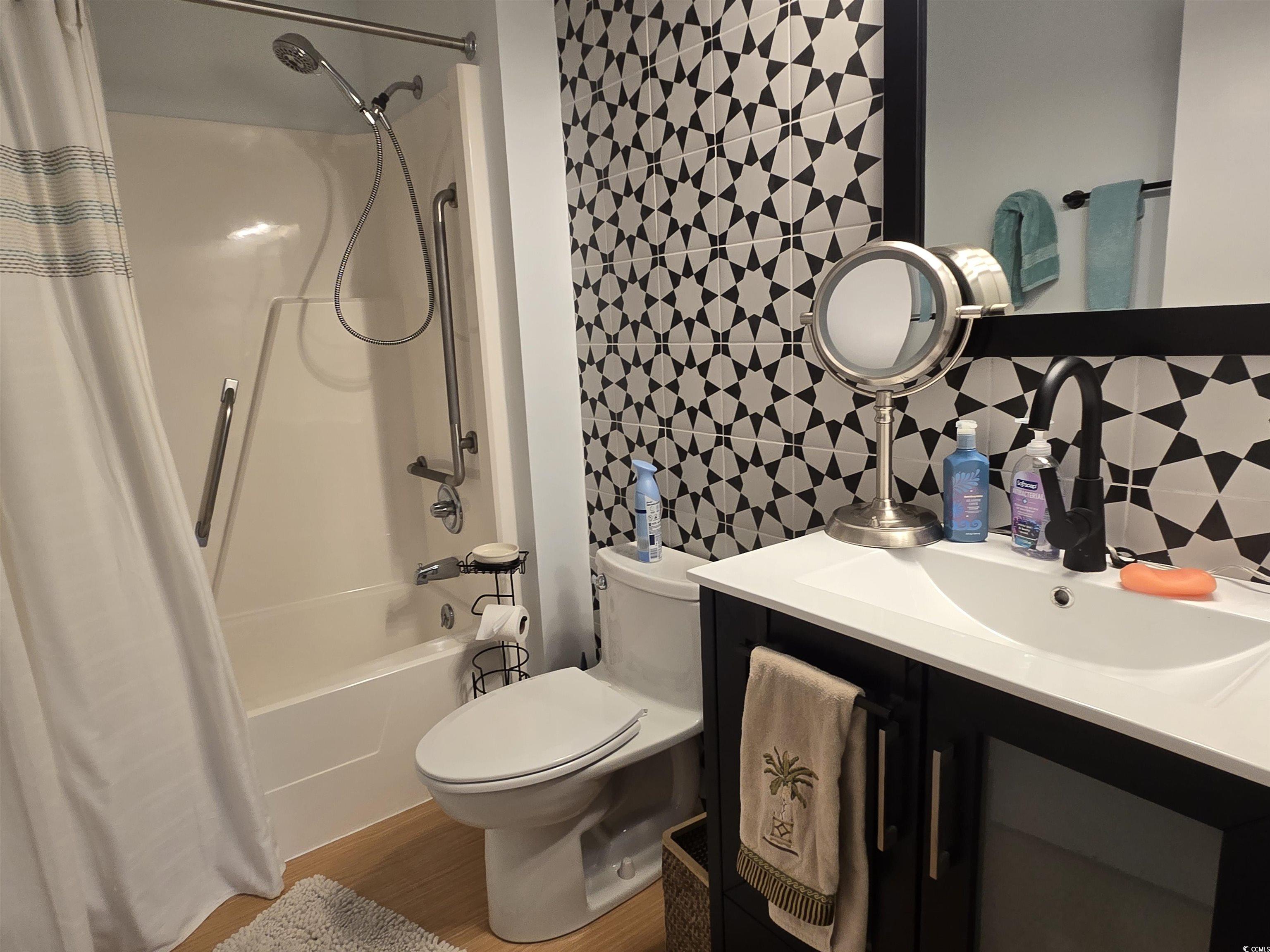 5001 Little River Road, Unit E108 Myrtle Beach, SC 29577 - Photo 14 of 25 Bathroom featuring shower / tub combo, tile walls, vanity, light wood-type flooring, and backsplash