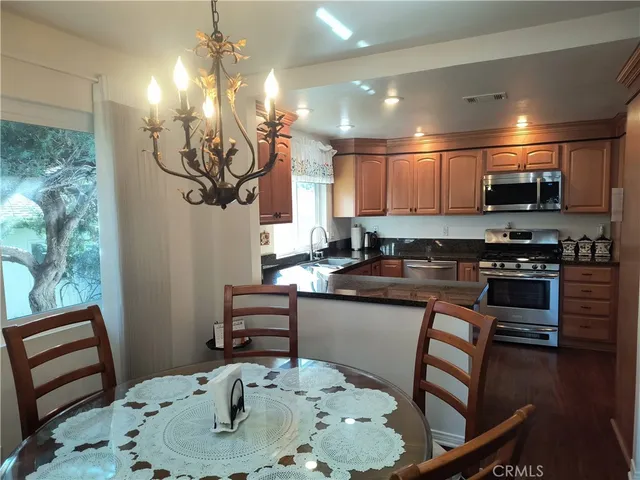 a kitchen with stainless steel appliances kitchen island granite countertop a sink a stove a dining table and chairs