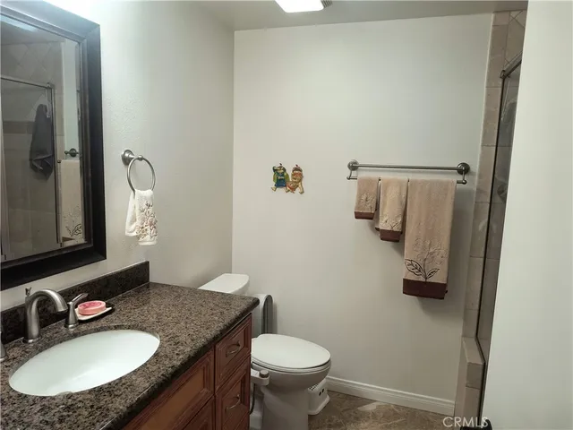 a bathroom with a granite countertop sink toilet and mirror