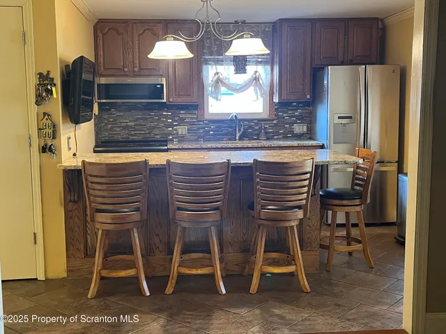 a kitchen with stainless steel appliances kitchen island granite countertop dining table chair and a refrigerator