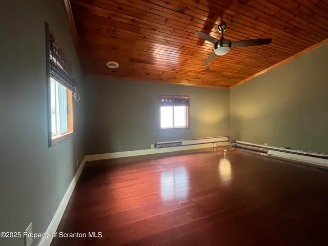 a view of an empty room with window and wooden floor