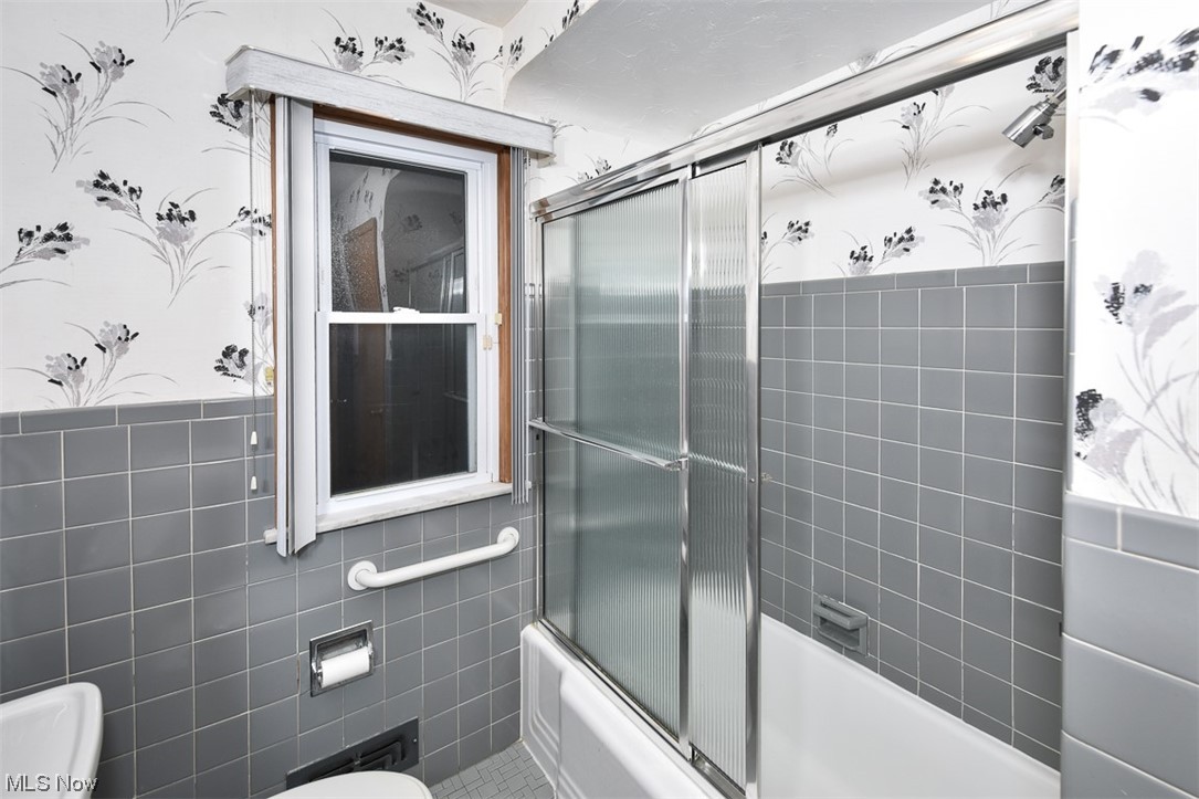 4026 Stonehaven Road Cleveland, OH 44121 - Photo 23 of 30 Bathroom with toilet, tile floors, bath / shower combo with glass door, and tile walls