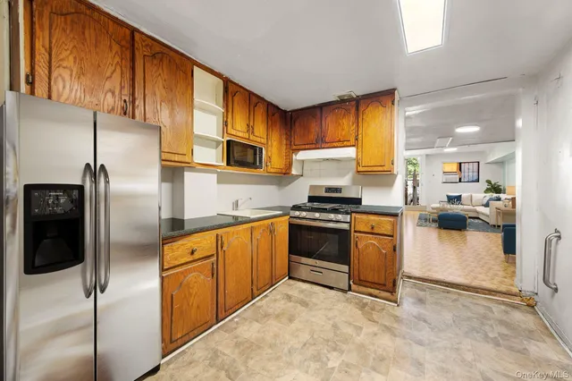 a kitchen with stainless steel appliances granite countertop a refrigerator a stove and a sink with wooden floor