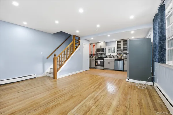 a view of a kitchen with wooden floor electronic appliances and stairs