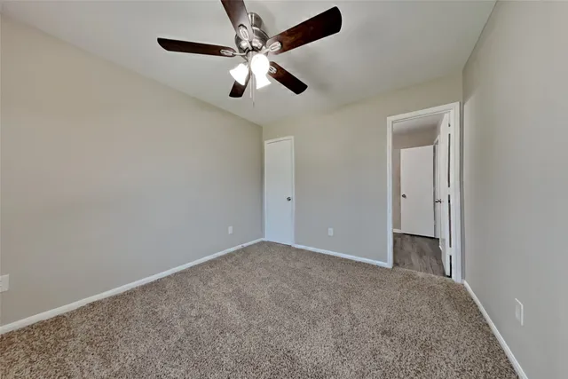 an empty room with a chandelier fan and windows