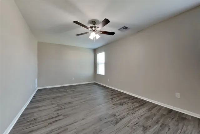 a view of an empty room with a window and wooden floor