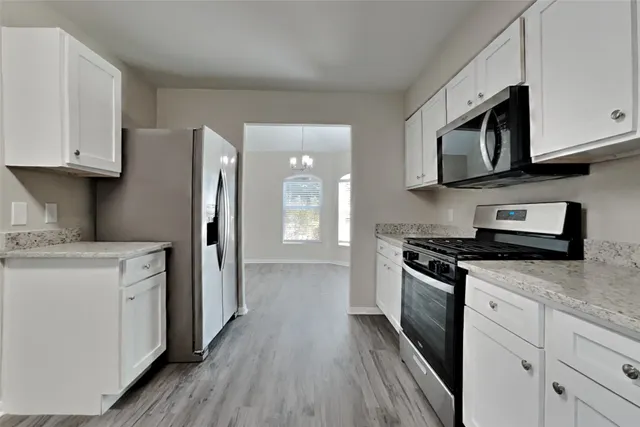 a kitchen with stainless steel appliances granite countertop a stove a refrigerator and a microwave