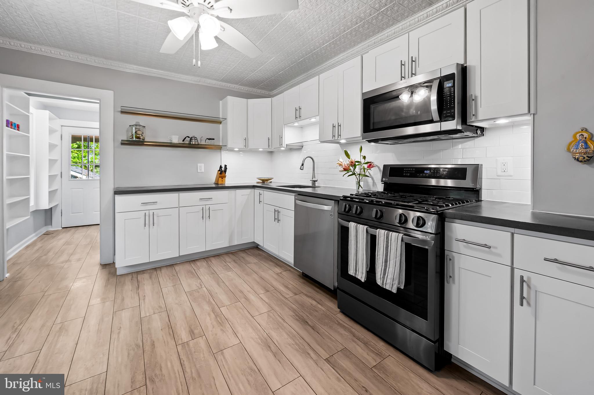 4605 Schenley Road Baltimore, MD 21210 - Photo 12 of 44 a kitchen with stainless steel appliances a stove microwave and white cabinets
