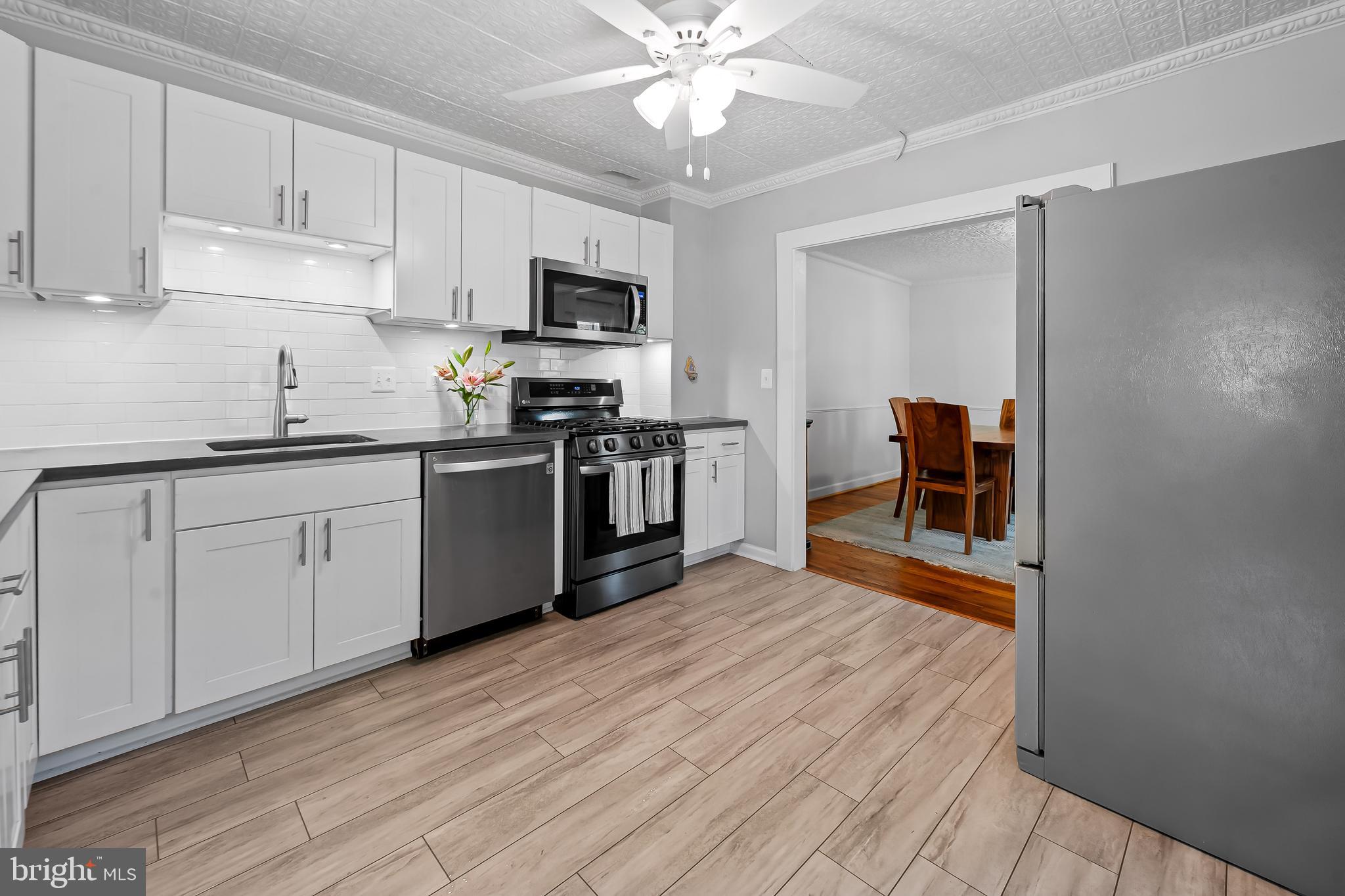 4605 Schenley Road Baltimore, MD 21210 - Photo 14 of 44 a kitchen with stainless steel appliances a sink dishwasher stove refrigerator and white cabinets with wooden floor