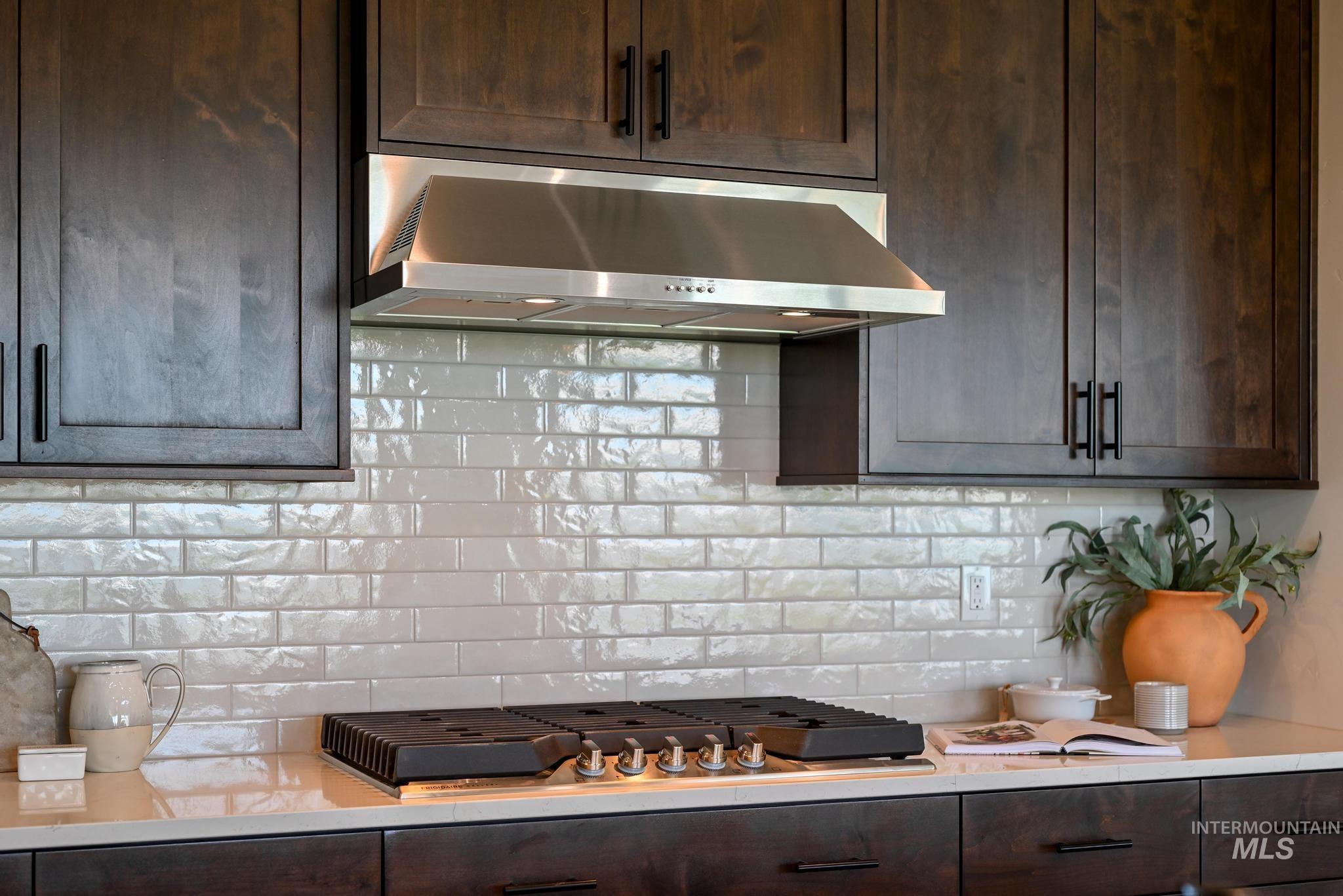 15086 Steel Cloud Avenue Caldwell, ID 83607 - Photo 13 of 41 Kitchen with exhaust hood, dark brown cabinets, light countertops, tasteful backsplash, and stainless steel gas stovetop
