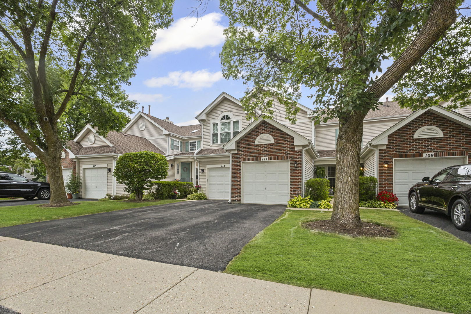 a front view of a house with a garden and trees
