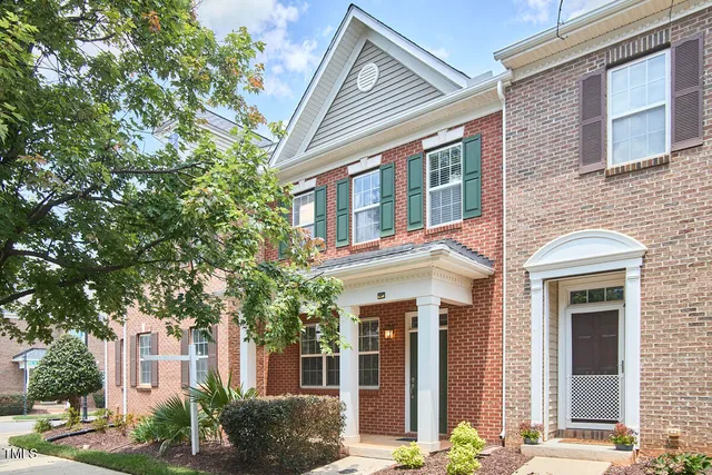 a front view of a brick house with a large windows and plants