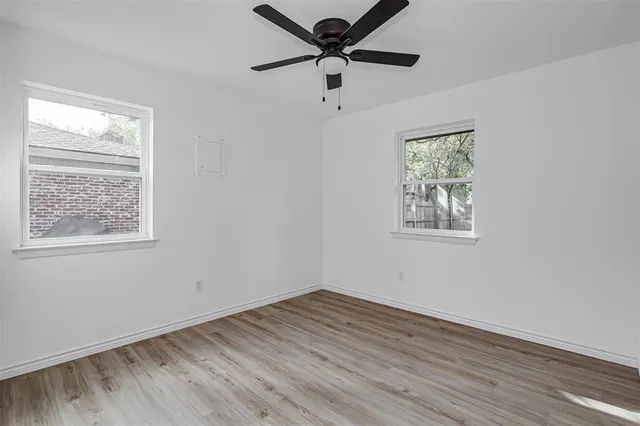 a view of empty room with wooden floor and fan